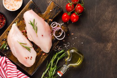 Taze çiğ tavuk fileto ile tuz, biber, soğan ve tereyağı ile ahşap bir tahta üzerinde koyu ahşap arka planda. Üst görünüm.