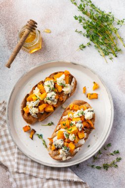 Fırınlanmış balkabağı sandviçi, mavi küflü Dorblu peynirli, bal ve kekik, beton, eski, aydınlık arka planda. Üst görünüm.