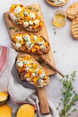 Fırınlanmış balkabağı sandviçi, mavi küflü Dorblu peynirli, bal ve kekik, beton, eski, aydınlık arka planda. Üst görünüm.