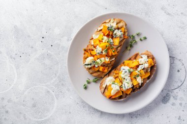 Fırınlanmış balkabağı sandviçi, mavi küflü Dorblu peynirli, bal ve kekik, beton, eski, aydınlık arka planda. Üst görünüm.
