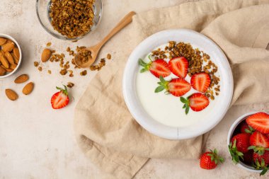 Kahvaltı tahıl gevreği ve eski bej masada taze çilek yapmak için malzemelerle dolu beyaz kasede Yunan yoğurdu. Üst görünüm.