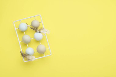 Beyaz antika metal tutacağında, arka planda tüyleri sarı olan hafif mavi yumurtalar. Mutlu Paskalyalar Kartı. Üst görünüm.