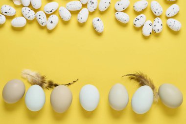Bir sürü beyaz tavuk yumurtası sarı arka planda duruyor. Fotokopi alanı olan en az yaratıcı paskalya kompozisyonu. Model yap. Bahar Mutlu Paskalyalar tebrik kartı. Üst görünüm.