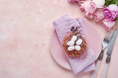 Paskalya baharı karşılama masası, güllerle süslenmiş ve mavi arka planda paskalya yumurtalarıyla süslenmiş. Üst Manzara. Metin için boşluk.