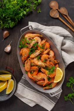 Sarımsaklı, limonlu ve maydanozlu kızarmış karides, siyah arkaplan, üst manzara, kopyalama alanı.