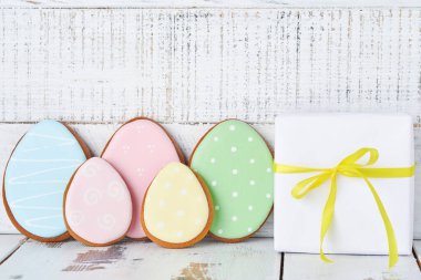 Paskalya tebrik kartı içinde renkli tavşanlar, yumurtalar, tavuklar ve havuçlu kurabiyeler olan beyaz ahşap arka planda fotokopi alanı olan zencefilli kurabiyeler. Model yap. Pankart. Üst görünüm.