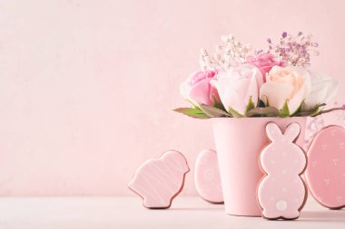 Paskalya arkaplan süslemesi, vazoda pembe güller, paskalya yumurtaları, pembe arka plan masasında tavşanlar ve piliçler. Kopya alanı ile Paskalya kavramı.