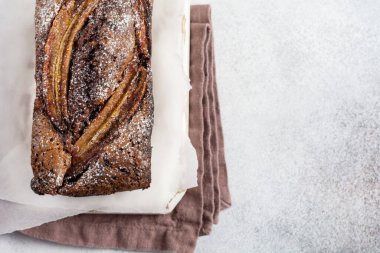 Tarçınlı muzlu ekmek ve hafif beton zemin üzerine krema serpiştirilmiş şeker. Seçici odak, metin için alan.