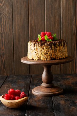 Pasta Anthill ahududu, çikolata ve fındıkla süslenmiş eski ahşap masa. Seçici odak.