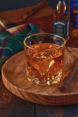 MOGILEV, BELARUS - 12 ARALIK 2020: Bir şişe Jack Daniel viskisinin karanlık, eski bir ahşap arka planda, dramatik bir ışık ve bir bardak viskinin yanında