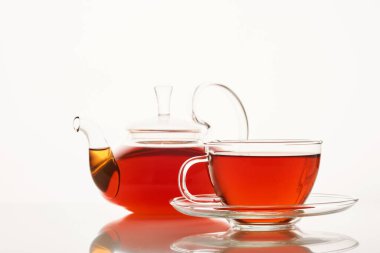 Beyaz arka planda bir bardak sıcak aromatik çay ve çaydanlık.