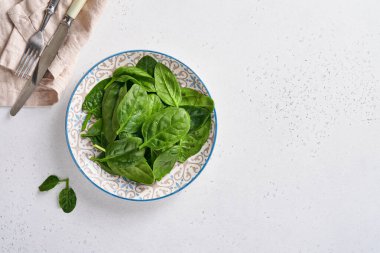 Seramik kapta taze ıspanak yaprakları açık gri beton arka planda. Model yap. Üst görünüm.