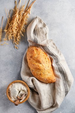 Açık gri beton masa, buğday unu ve kulaklarda tohum bulunan ev yapımı ekmek. Üst görünüm düzlüğü kopyalama alanı ile yatıyordu