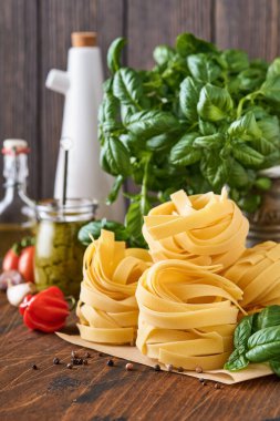 Beyaz zemin üzerine kahverengi kağıtlı ev yapımı tagliatelle makarna zeytinyağı, sosis sosu, fesleğen ve sarımsak..