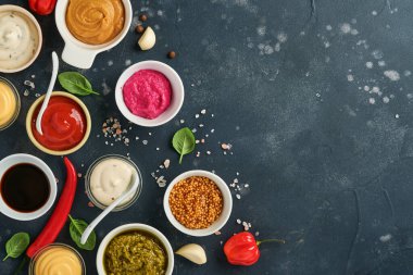 Kâselerdeki soslar; ketçap, mayonez, hardal, soya sosu, bbq sosu, pesto, chimichurri, hardal tanecikleri. Üst görünüm kopyalama alanı.