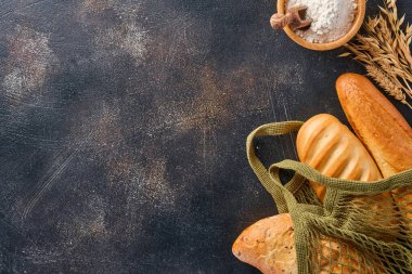 Çeşit çeşit gevrek ekmek ve çörekler torba ya da alışveriş torbası, buğday unu ve kulaklar kahverengi beton arka plan masasında. Üst görünüm düzlüğü kopyalama alanı ile yatıyordu