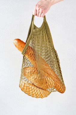 El ele tutuşan kadın ya da pamuk alışverişçisi gri arkaplandan önce tekrar kullanılabilir ekmek torbası. Sıfır atık. Mesaj için yer var. Model.