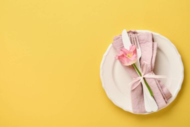 Sarı masa üzerinde çiçek dekoru olan Paskalya sofrası. Zarif bir akşam yemeği. Model yap. Üst görünüm.