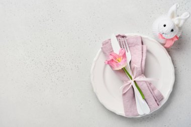 Gri masa üzerinde çiçek dekoru olan Paskalya sofrası. Zarif bir akşam yemeği. Model yap. Üst görünüm.