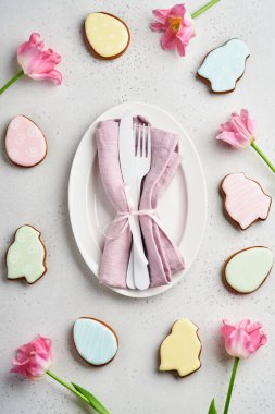 Gri masa üzerinde çiçek dekoru olan Paskalya sofrası. Zarif bir akşam yemeği. Model yap. Üst görünüm.