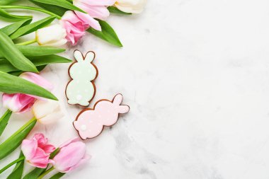 Paskalya sofrasında çiçek dekoru ve beyaz masada paskalya zencefilli ekmek. Zarif bir akşam yemeği. Model yap. Üst görünüm.