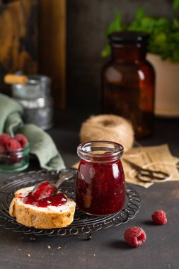 Cam kavanozda ahududu reçeli ve eski retro arka planda taze ahududu meyveli sandviç. Seçici odak.