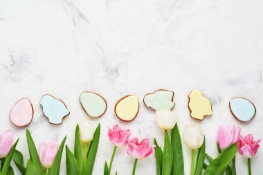 Paskalya sofrasında çiçek dekoru ve beyaz masada paskalya zencefilli ekmek. Zarif bir akşam yemeği. Model yap. Üst görünüm.