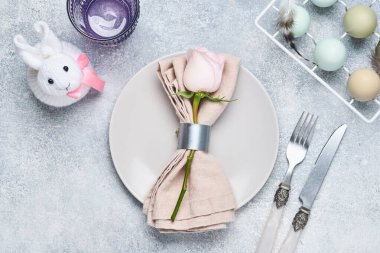 Gri arka planda pembe plakalı gül çiçekleri olan zarif masa ayarı. Zarif bir tatil yemeği. Üst Manzara. Metin için boşluk.