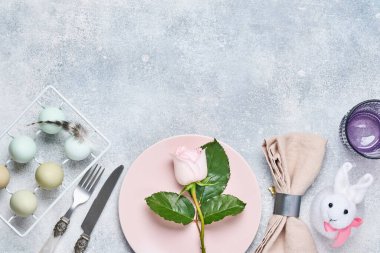 Gri arka planda pembe plakalı gül çiçekleri olan zarif masa ayarı. Zarif bir tatil yemeği. Üst Manzara. Metin için boşluk.