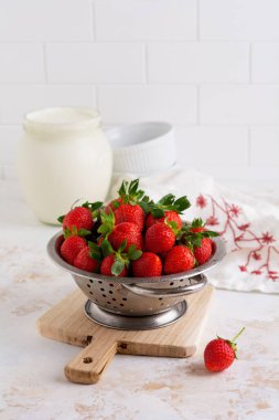 Taze çilekler kevgir kevaşesinde lezzetli ve beyaz taş arka planda fotokopi alanı var. Seçici odak.