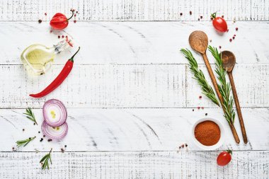 Baharatlı Pişirme Arkaplanı: biber, biberiye, paprika, limon, soğan, kuşkonmaz, zeytinyağı, domates, parmesan peyniri, ahşap zemin üzerinde pişirme tahtası ve peçete. Mutfak afişi. Üst görünüm.
