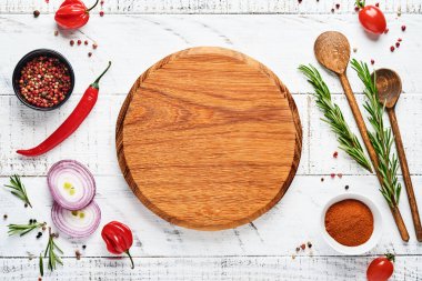 Baharatlı Pişirme Arkaplanı: biber, biberiye, paprika, limon, soğan, kuşkonmaz, zeytinyağı, domates, parmesan peyniri, ahşap zemin üzerinde pişirme tahtası ve peçete. Mutfak afişi. Üst görünüm.
