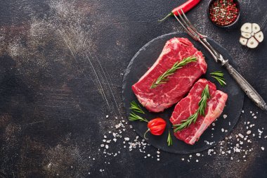 Biberiye ve baharatlı iki çiğ biftek. Siyah taş kesme masasının üstünde düz bir görünüm vardı..