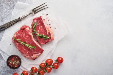 İki çiğ biftek New York biberiyeli ve siyah taşlı baharatlar açık beyaz taşlı arka planda kesme tahtası. Üst Manzara. Model.