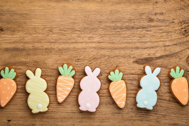 Paskalya kompozisyonu, paskalya tavşanları ve havuçlu kurabiyeler ahşap zemin üzerinde zencefilli ekmek. Kutlama konsepti ya da fotokopi alanı olan tebrik kartı. Düz yatış, üst görünüm.