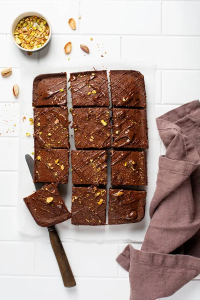 Fıstıklı çikolatalı kareler ve beyaz arkaplanda beyaz kağıt üzerinde çilek, üst manzara, yatay kompozisyon. Düz yiyecek.