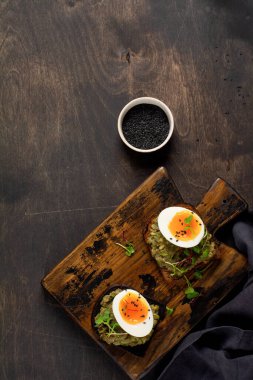 Kahvaltıda avokado, yumurta ve kızarmış ekmek ile birlikte sağlıklı bir sandviç. Sağlıklı beslenme konsepti. Üst görünüm