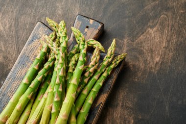 Kuşkonmaz. Eski siyah ahşap arka planda pişmeye hazır taze kuşkonmaz sürüsü. Üst görünüm kopyalama alanı.