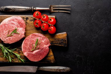 Ahşap tahtada iki taze Paris usulü çiğ biftek, eski ahşap arka planda tuz, biber ve rosmary. Kara Angus. Üst görünüm