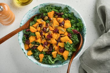 Lahanalı sonbahar salatası, kavrulmuş balkabağı, tohumlar ve kase içinde kurutulmuş kızılcık. Gri arka plan. Model yap. Üst görünüm.