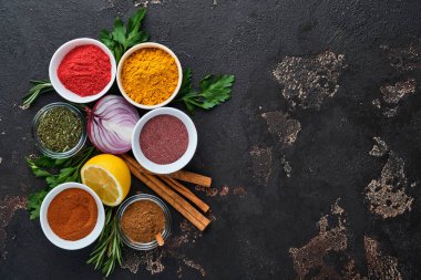 Siyah taştan bir arka planda Hint baharatları ve otları. Bir kaşıkta zerdeçal, dereotu, paprika, tarçın, safran, fesleğen ve biberiye. Üst Manzara. Model.
