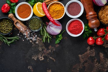 Siyah taştan bir arka planda Hint baharatları ve otları. Bir kaşıkta zerdeçal, dereotu, paprika, tarçın, safran, fesleğen ve biberiye. Üst Manzara. Model.