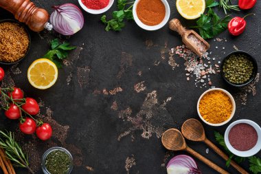 Siyah taştan bir arka planda Hint baharatları ve otları. Bir kaşıkta zerdeçal, dereotu, paprika, tarçın, safran, fesleğen ve biberiye. Üst Manzara. Model.