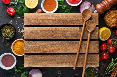 Siyah taştan bir arka planda Hint baharatları ve otları. Bir kaşıkta zerdeçal, dereotu, paprika, tarçın, safran, fesleğen ve biberiye. Üst Manzara. Model.