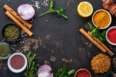 Siyah taştan bir arka planda Hint baharatları ve otları. Bir kaşıkta zerdeçal, dereotu, paprika, tarçın, safran, fesleğen ve biberiye. Üst Manzara. Model.