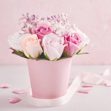 Açık pembe arka planda pembe yuvarlak kutuda güzel narin güller olan şenlikli bir kompozisyon. Anneler Günün kutlu olsun. Kare resim.