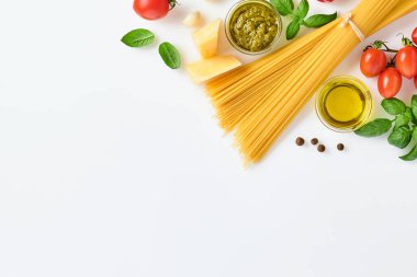 Spagetti, taze domates, otlar ve baharatlar. Beyaz arka planda izole edilmiş sağlıklı besin bileşenleri, üst görünüm. Model.