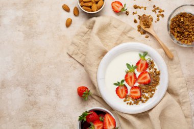 Kahvaltı tahıl gevreği ve eski bej masada taze çilek yapmak için malzemelerle dolu beyaz kasede Yunan yoğurdu. Üst görünüm