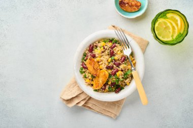 Meksika siyah fasulyeli kinoa salatası ve karamelize edilmiş limon açık gri beton arka planda eski moda kil kasede. Geleneksel Meksika mutfağı. Üst görünüm, modelle.