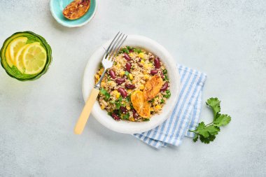 Meksika siyah fasulyeli kinoa salatası ve karamelize edilmiş limon açık gri beton arka planda eski moda kil kasede. Geleneksel Meksika mutfağı. Üst görünüm, modelle.